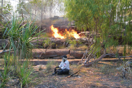Indigenous ranger in front of fire in the bush