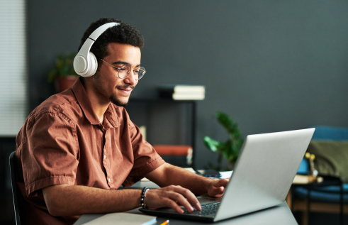 Male student with headphones looking at a laptop