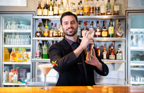 A person mixing beverages behind a bar