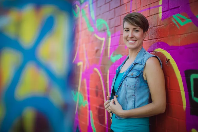 CDU Creative Arts student standing infront of a wall covered in colourful graffitti