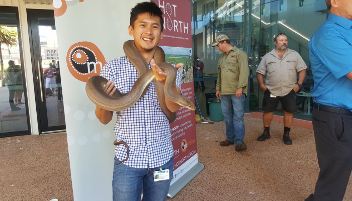 CDU student Damian stands holding a snake