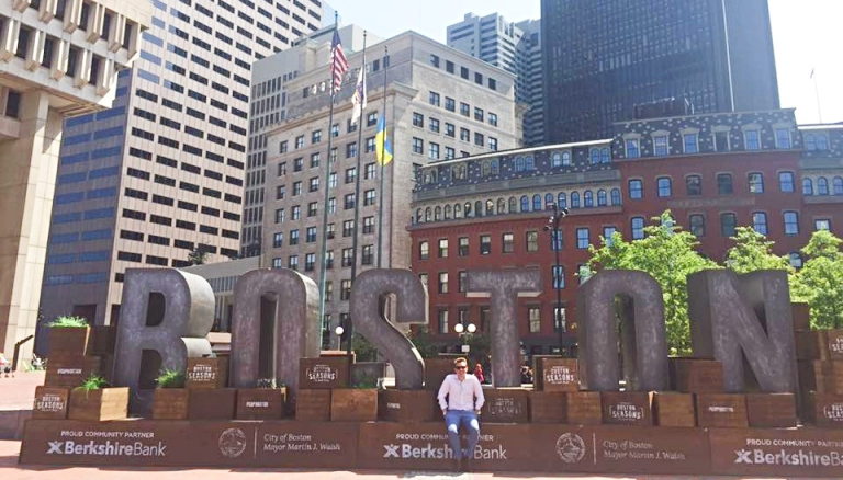 CDU student Paul Larder in front a big sign in Boston USA