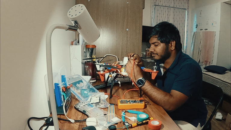 CDU student Sai Ram working at a desk surrounded by computer gear