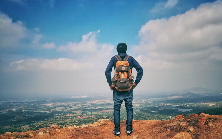 Male traveller with backpack overlooking a mountain view