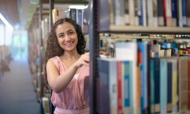 CDU student Nancy Soliman in the library choosing a book.