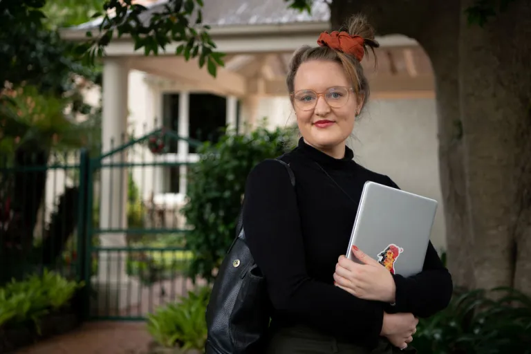 CDU student Claire Bowditch with laptop in front of her home