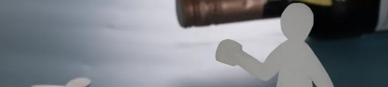 Paper cutout of man menacing paper cutout of child; wine bottle in background