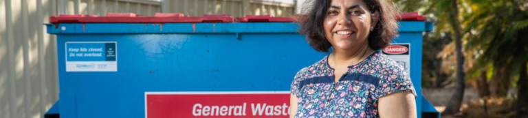 Woman in front of large general waste bin