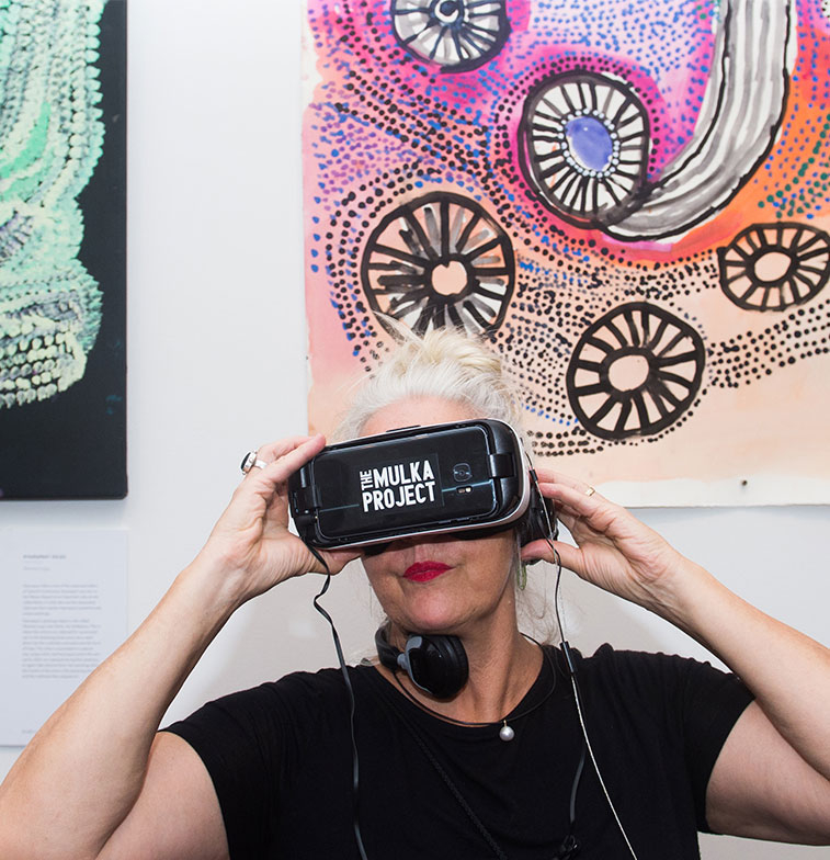 A CDU Art Gallery visitor views the interactive immersive reality video and audio artwork “Daday’yun at The Mulka Project”, 2016 by Bawuli Marika, created under the auspices of Buku Larrngay Mulka Arts Centre, Yirrkala, NT in 2016