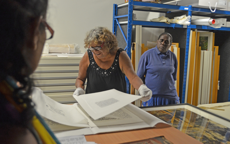 Karen Rogers (Ngukurr Arts) and Rose Wilfred (Numbulwar Numburindi Arts) examine  prints at CDU Art Collection and Gallery