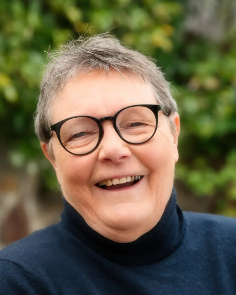 Professor Helen Verran Smiling in front of green trees