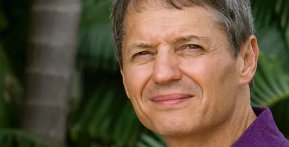 Keith Christian head and shoulders with palm tree trunk and large green leaves in the background