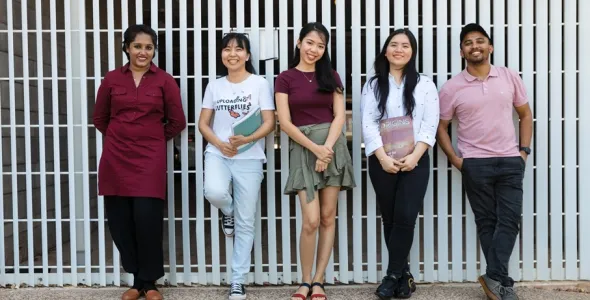 students leaning on wall outside