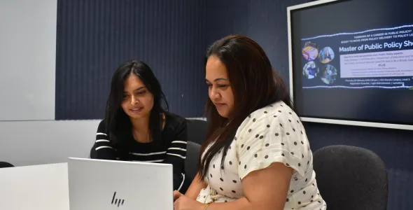 two students looking at a laptop talking