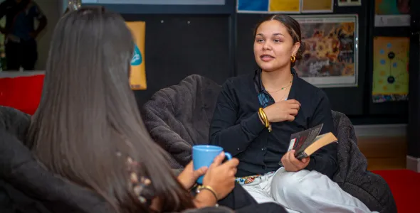 Two students seated down with one students back facing the front