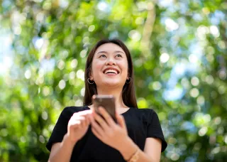 Female with smart phone, green foliage background