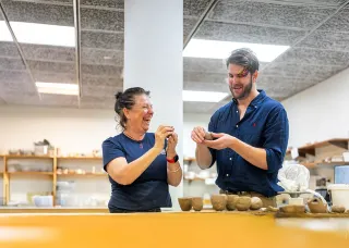 Two people making pots from clay