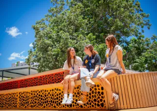 Three students sitting on bench at Danala city campus 