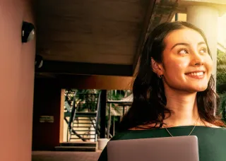 Female student looking happy on a bright tropical campus.