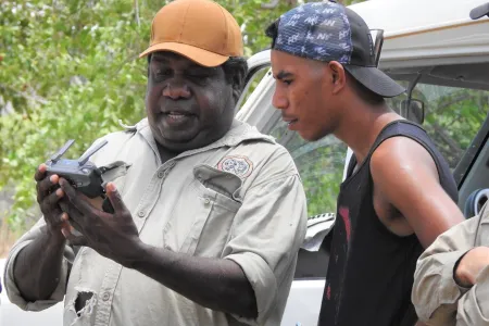 Traditional Owner Ryan Barrowei teaches his cousin Mark Hunter how to use the drone to see Country after cool fire management at Jarrangbarnmi.
