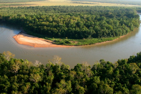 Aerial view of the bend in a river surrounded by dense forest