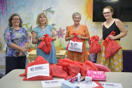 Territory Families, Housing and Communities Deputy CEO Jeanette Kerr, CDU Secretary Professor Hilary Winchester AM, Executive Officer Susan Crane and TFHC Director of Housing Pathways Emma Clee present donated essential goods to women’s refuges.