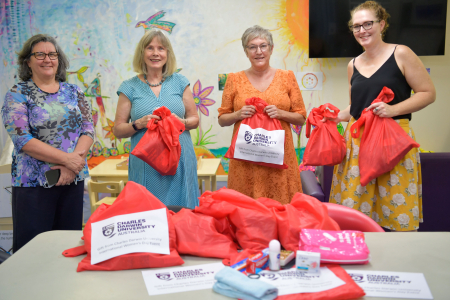Territory Families, Housing and Communities Deputy CEO Jeanette Kerr, CDU Secretary Professor Hilary Winchester AM, Executive Officer Susan Crane and TFHC Director of Housing Pathways Emma Clee present donated essential goods to women's refuges.