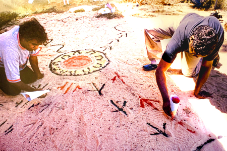 men drawing animal tracks in sand