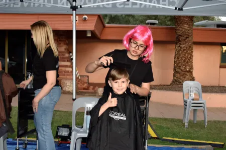 child getting hair cut gives thumbs up