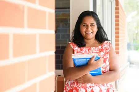 Indigenous Australian teacher holding books in regional school