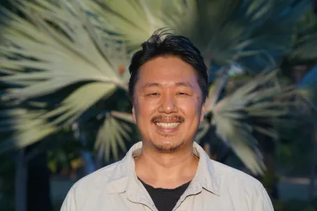 Yusuke Fukuda head and shoulders, with out of focus palm fronds in the background
