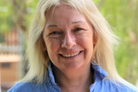 student alicia boyle with should length blonde hair stands in garden wearing blue shirt