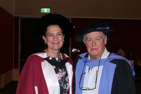 Two professors pose in regalia 