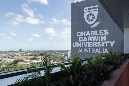 Image of University branding taken at elevation with the sprawling Darwin CBD in the background. 
