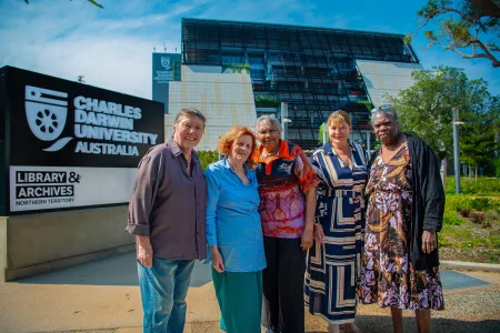 Five women stand outside the front of Charles Darwin University's new campus in the Darwin CBD. 