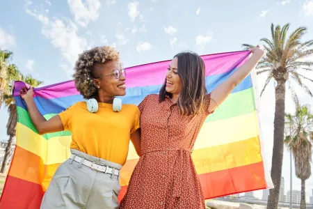 Two people holding a brightly coloured flag