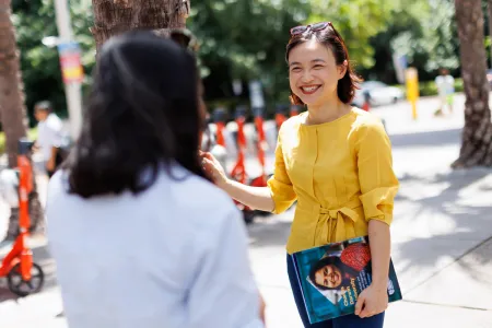 Image of an Asian student talking with another student with a smile