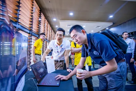 Students and staff at the CDU IT Code Fair looking at a laptop.
