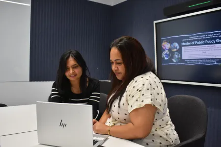 two students looking at a laptop talking