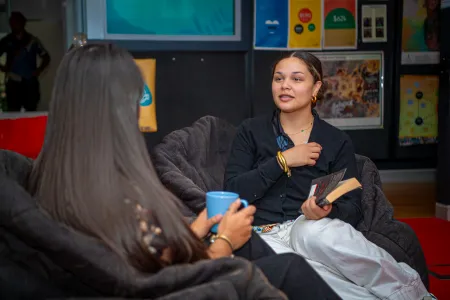Two students seated down with one students back facing the front