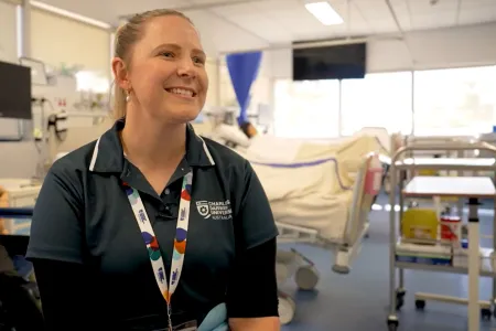 Nursing lecturer sits in front of hospital beds