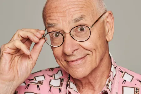 Image of Dr Karl holding his glasses and looking into camera