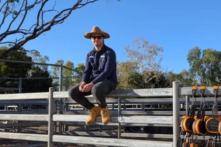Portrait of Adam Moloney sitting on a fence of a livestock pen