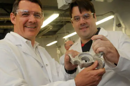 Chief Minister Michael Gunner (left) and Steven Camilleri, inventor of the LightSPEE3D Printer. Steven holds an automotive part produced by the printer. 