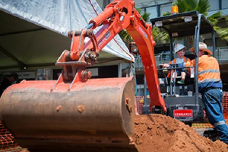 Jackson Doubleday rides the digger at Open Day with help from VET Lecturer Barry Whalan