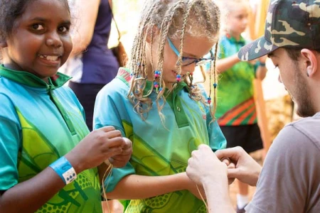 Teshania Sing and Poppy Bender with Isaiah Lee learning how to make a friendship band