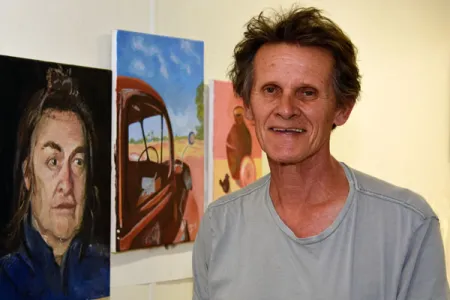 Art teacher Henry Smith inspects some of the paintings in the end-of-year exhibition.