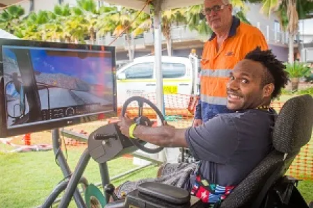 Jerimus Dimpamala tests his skills at the new dump truck simulator at CDU Open Day. Pictured with VET lecturer Peter Bacon