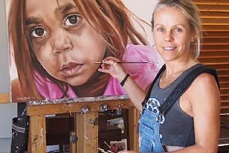 Dr Al Strangeways puts the finishing touches to one of the works in “Community: The People of the School” exhibition. Image: Bean Strangeways