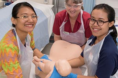 (From left) Cinthya Riris, CDU Midwifery lecturer Angela Bull and Sukma Adnyani simulate a birth using a mannequin. Photo: Julianne Osborne